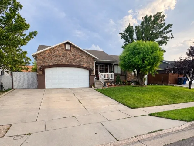 Stone veneer exterior with an arched garage door, concrete driveway, and a covered porch with white railings