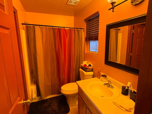 Vanity with integrated sink, wood cabinetry, and a framed wall mirror