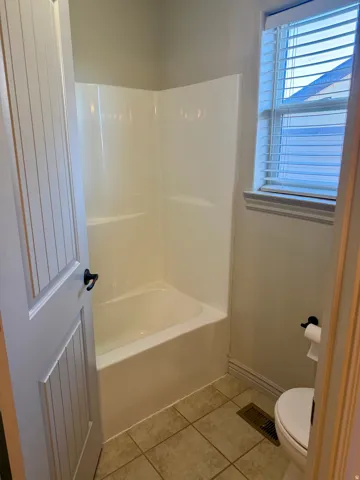 White bath and shower combination with a window, complete with blinds