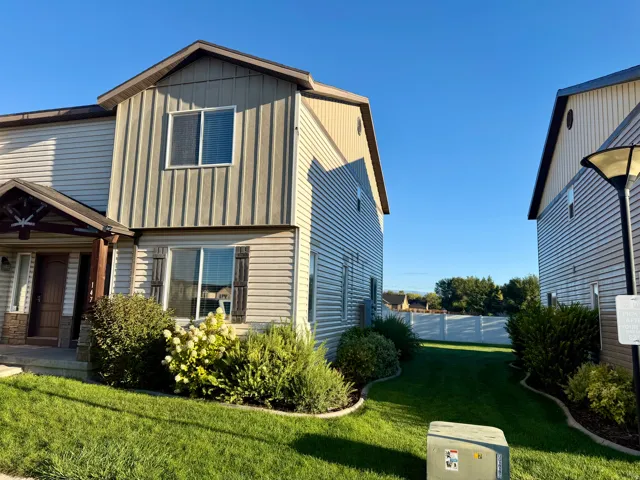 Siding exterior with vertical and horizontal panels, covered front porch, and manicured landscaping