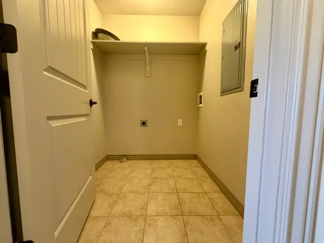 Laundry area with light-toned tiled flooring, built-in shelving, and a panel door