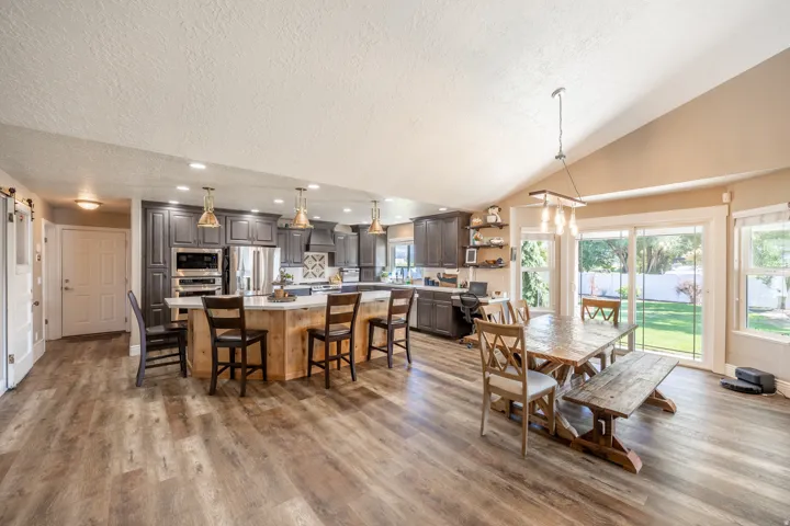 Expansive room featuring wood-finish flooring, a kitchen island with seating,, and sliding glass doors to a backyard