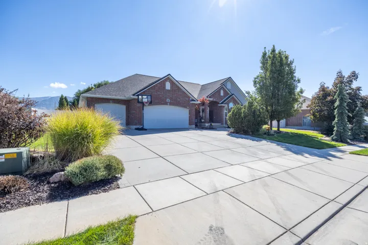Brick exterior with a dark shingle roof, concrete driveway, and attached two-car garage