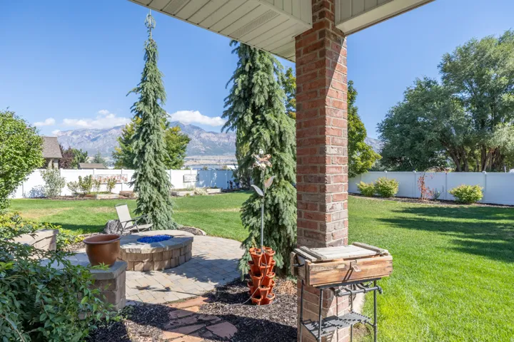 Expansive backyard featuring a manicured lawn, paver patio with built-in fire pit, and fabulous views of the mountains.
