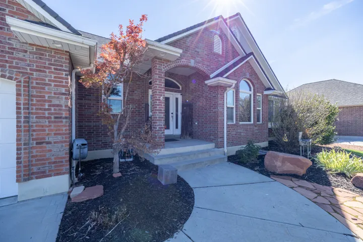 Brick exterior with arched entry, arched windows, concrete walkway, and landscaped garden beds