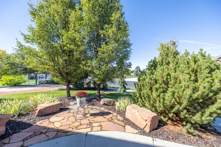 Stone flagstone path with natural rock accents, surrounded by mature trees, varied shrubs, and groundcover