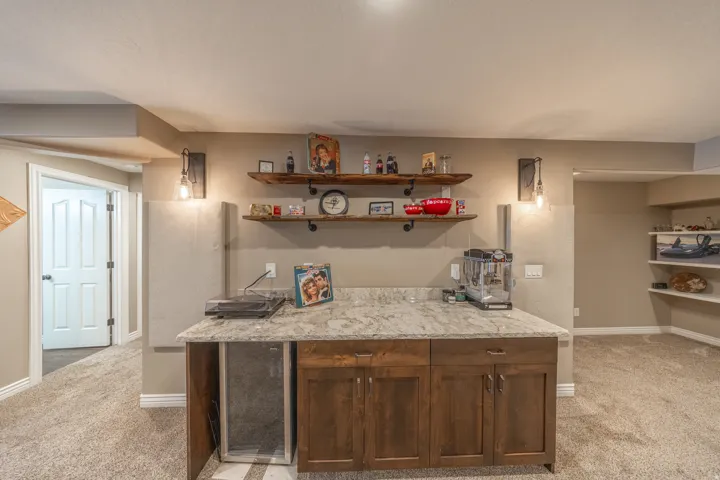 Built-in cabinetry with wood-finish doors, stone-look countertop, and open shelving