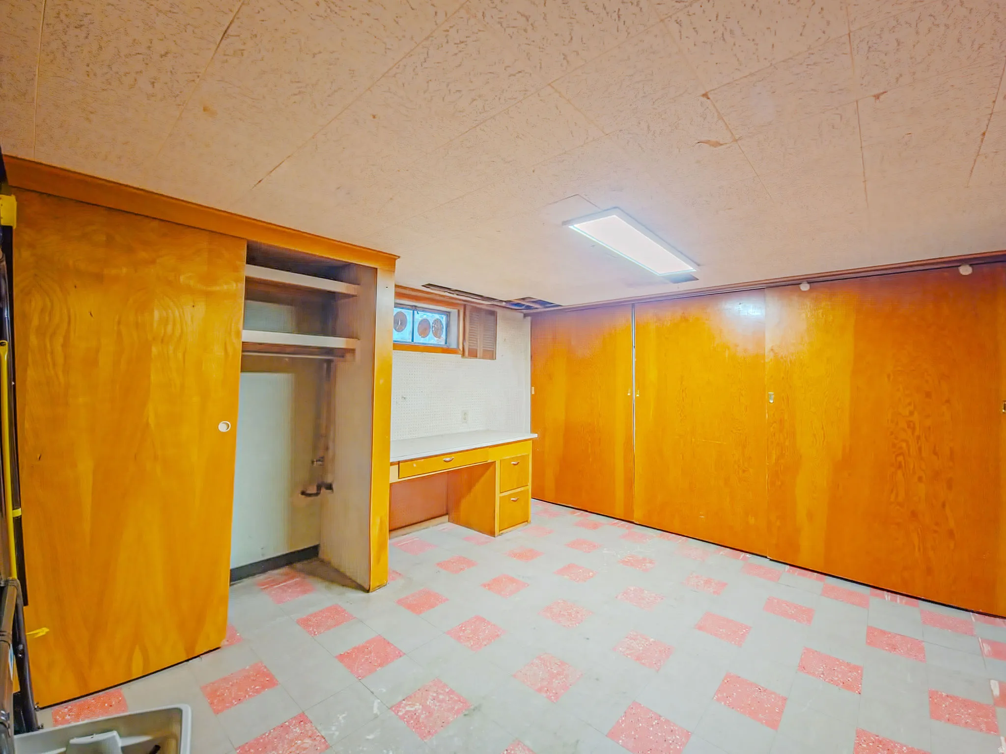 Room featuring built-in desk, built-in shelving, wood-paneled walls, sliding closet doors, and patterned floor tiles
