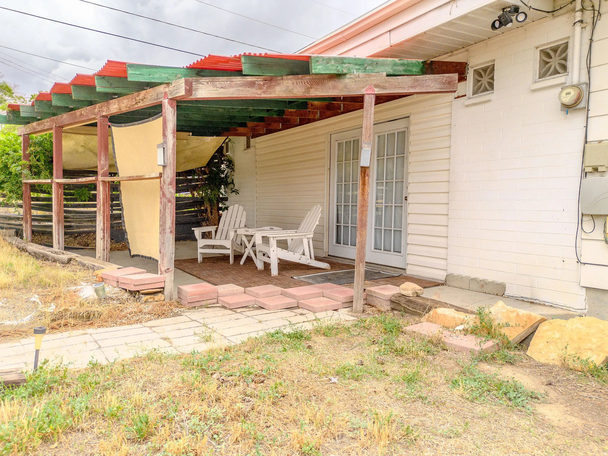 Covered patio with a wood pergola structure, siding exterior, and dual glass-paned doors