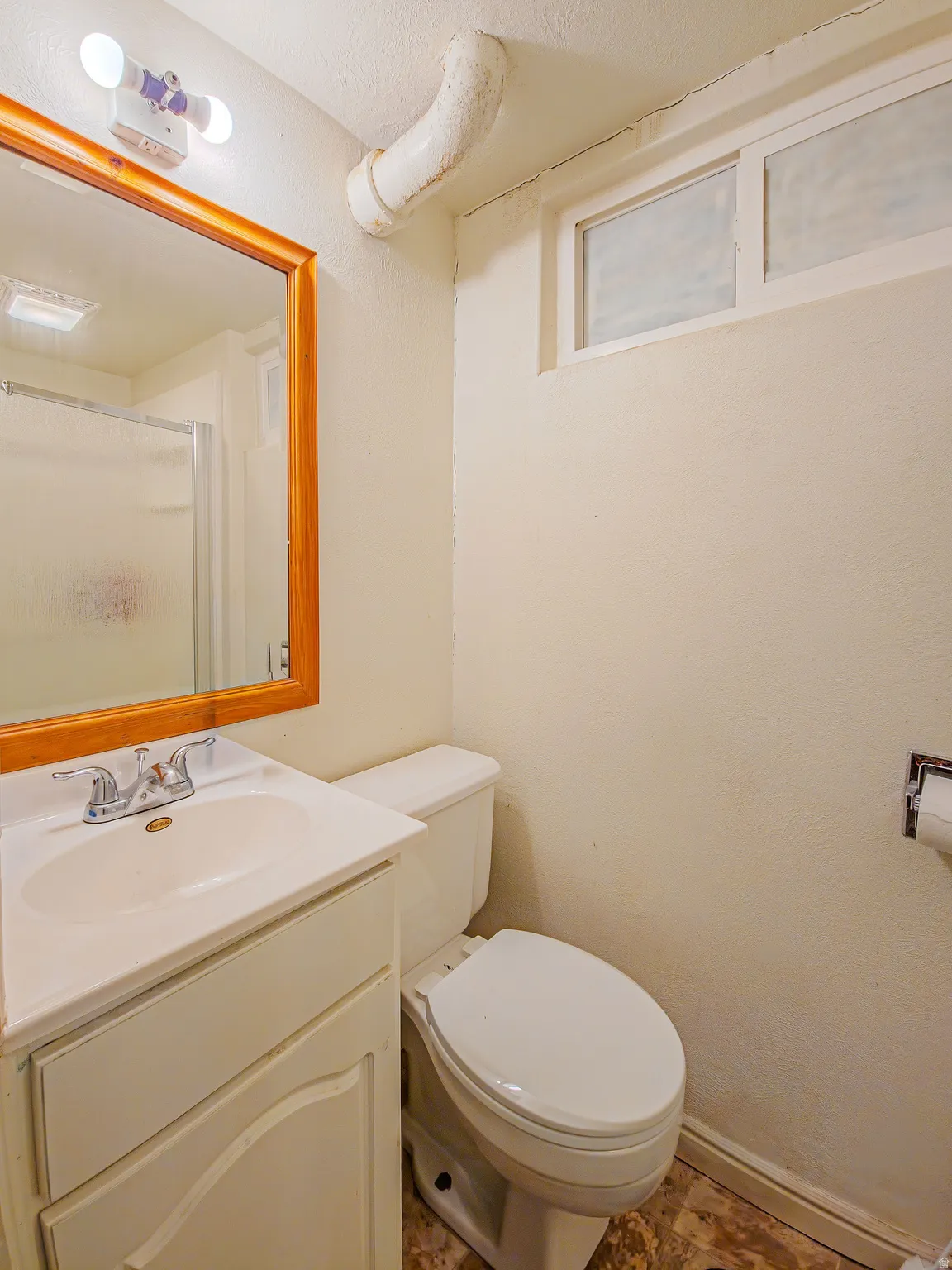 Vanity with integrated sink, wood-framed mirror, and two-light fixture