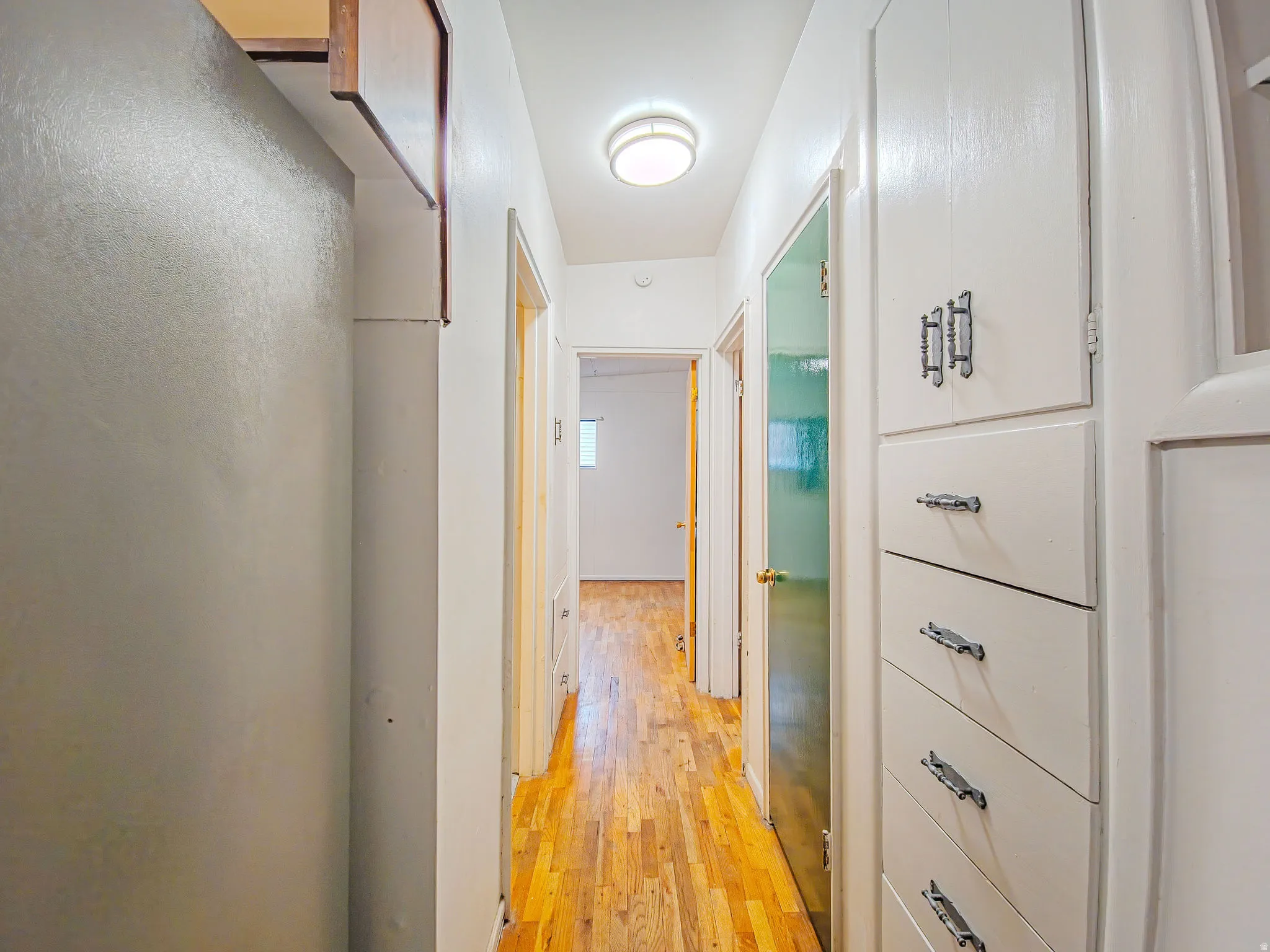 Hallway featuring wood-finish flooring, built-in cabinetry with decorative hardware, and a ceiling-mounted light fixture