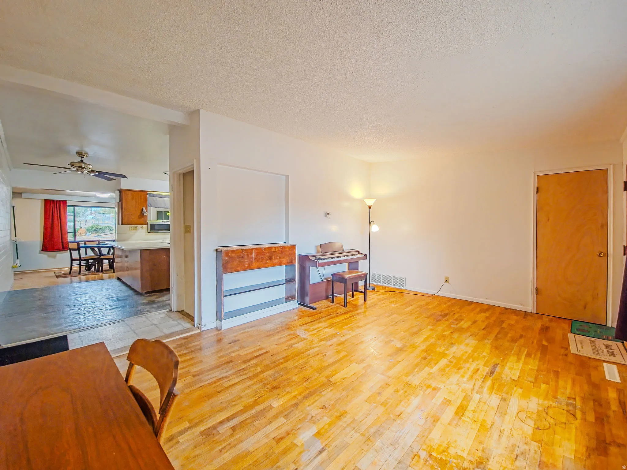 Hardwood flooring throughout the main area, with a functional pass-through opening to the kitchen featuring a ceiling fan