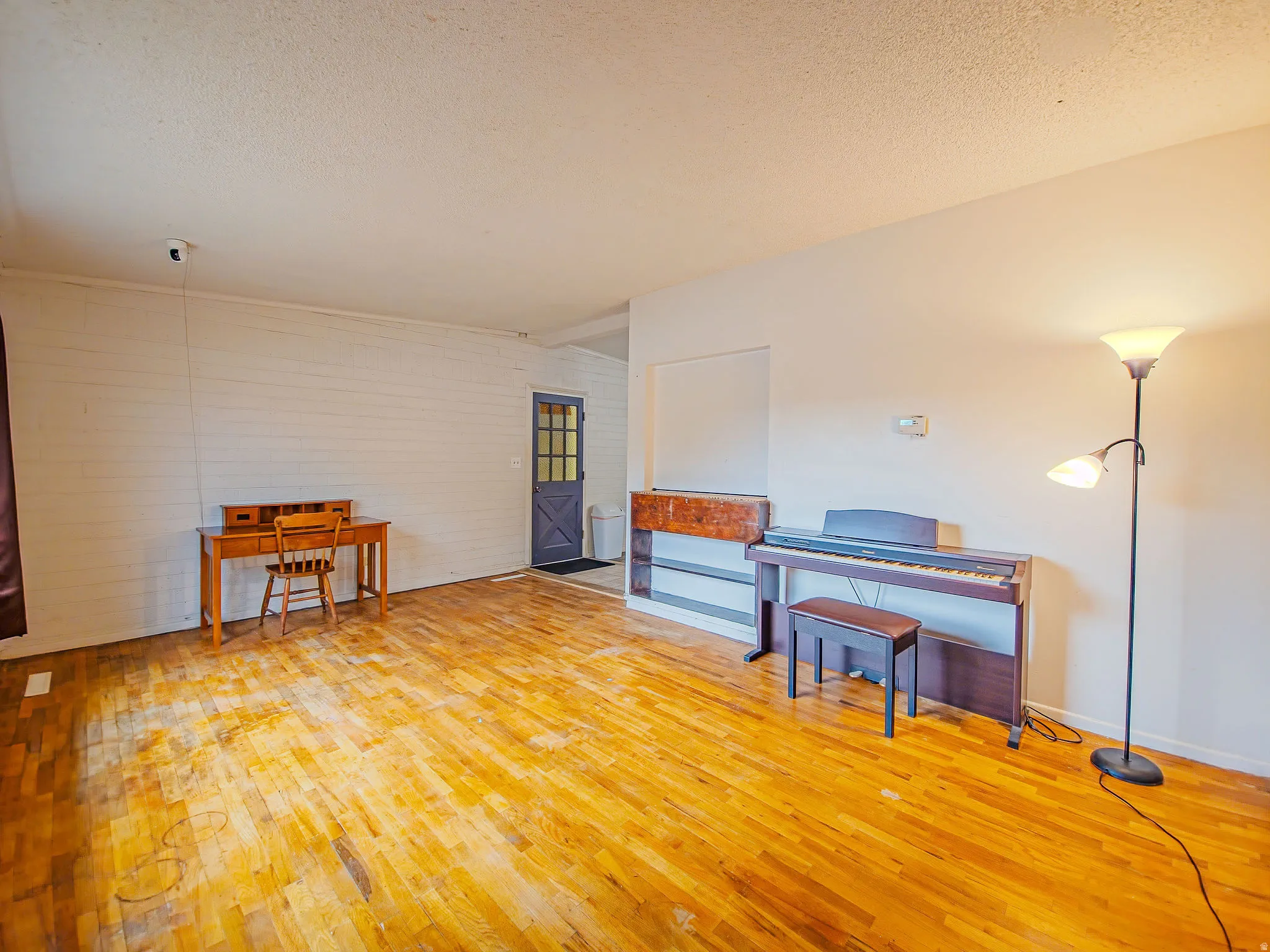 Hardwood flooring throughout, white painted walls, and a paneled entry door