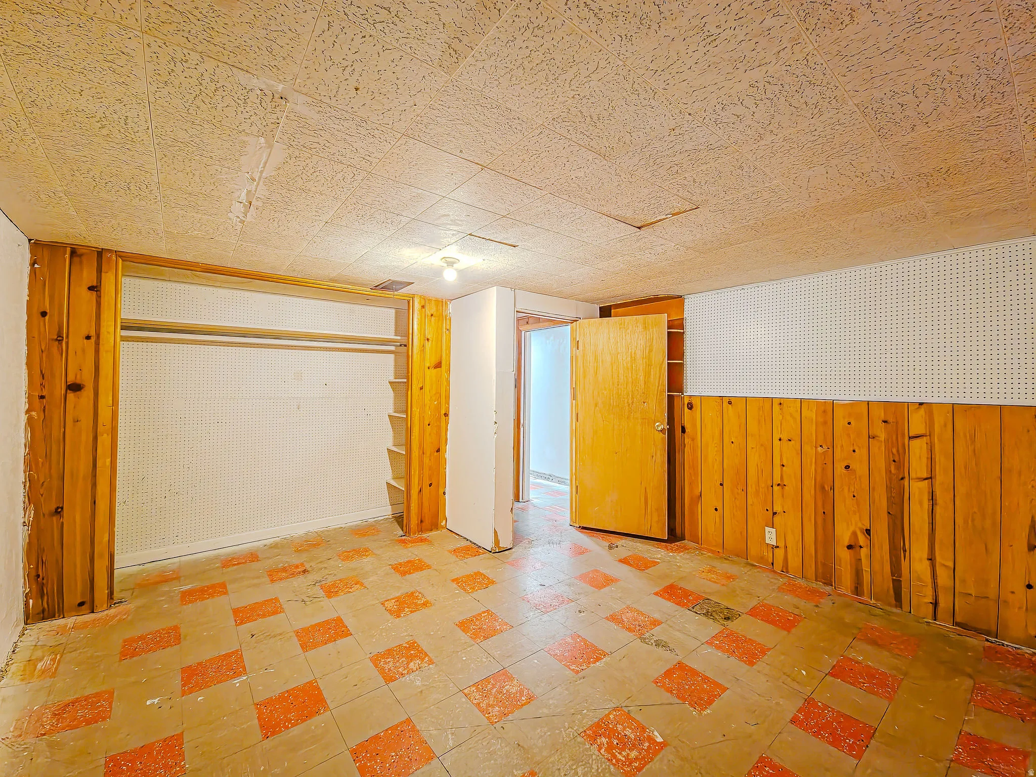 Wood paneling, pegboard wall, built-in shelving, checkered flooring, and a flush mount light fixture