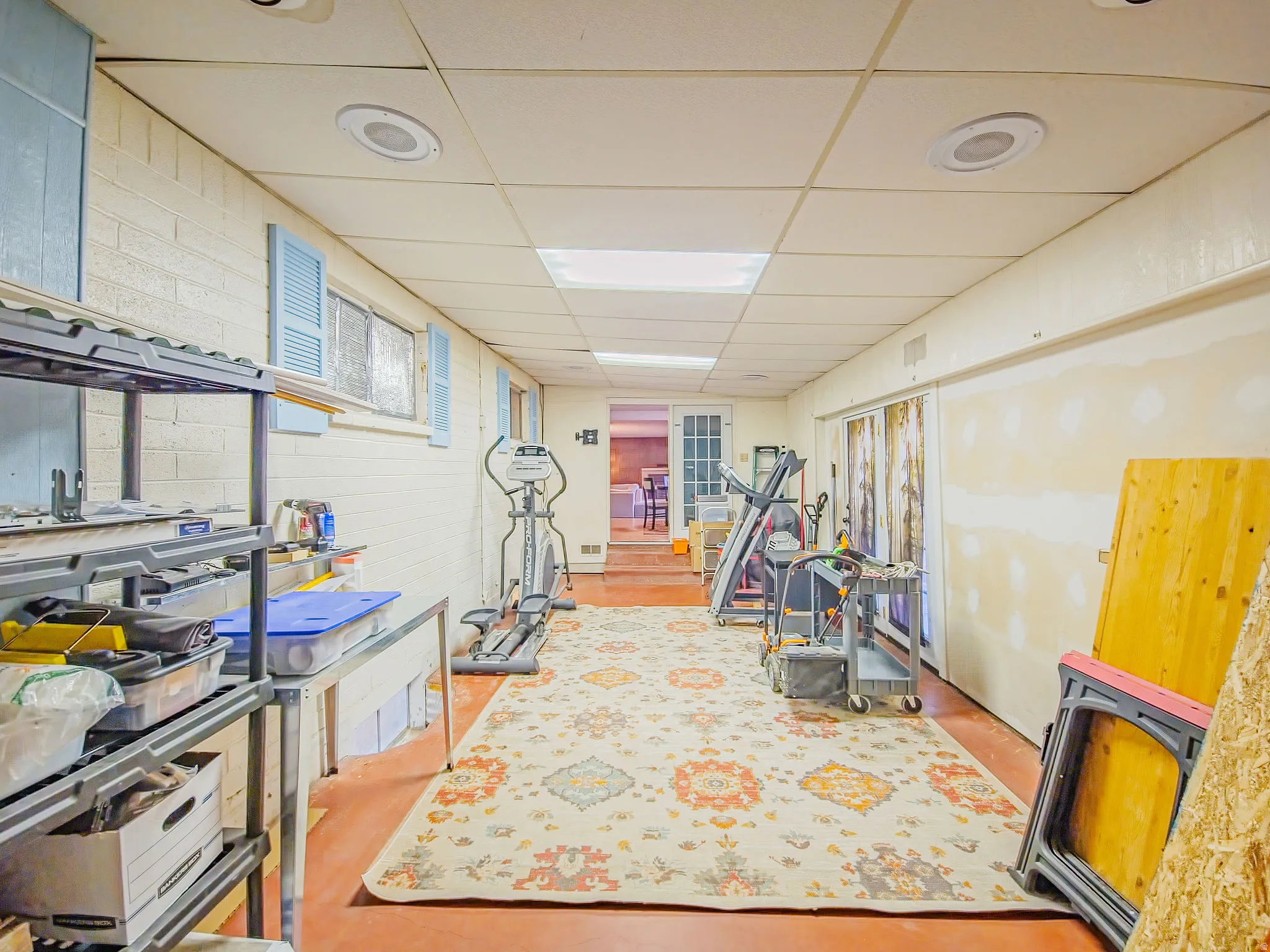 Recessed lighting with a drop ceiling, white painted brick walls, and a finished flooring surface