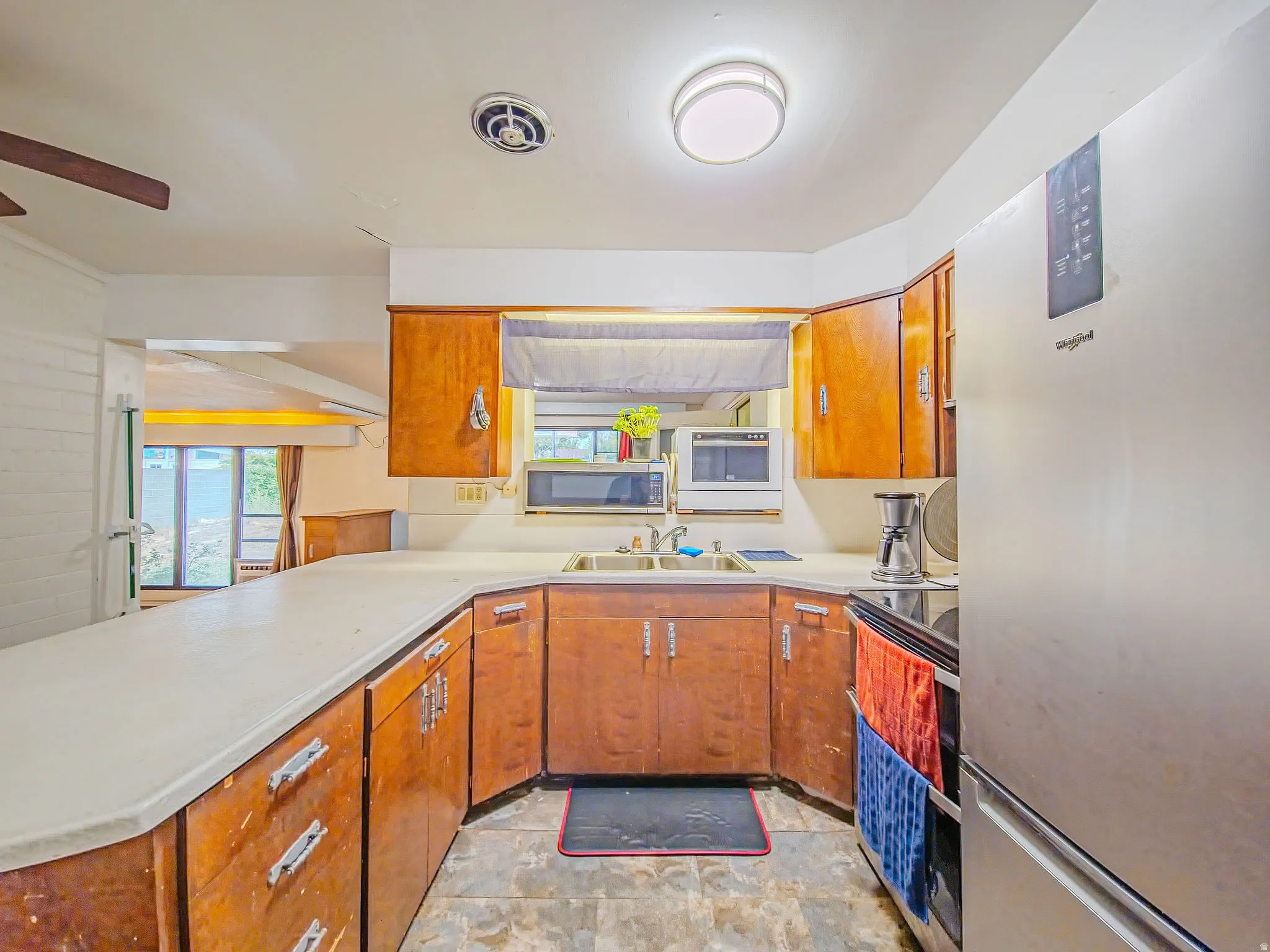 Kitchen with wood-finish cabinetry, solid surface countertops, and integrated sink