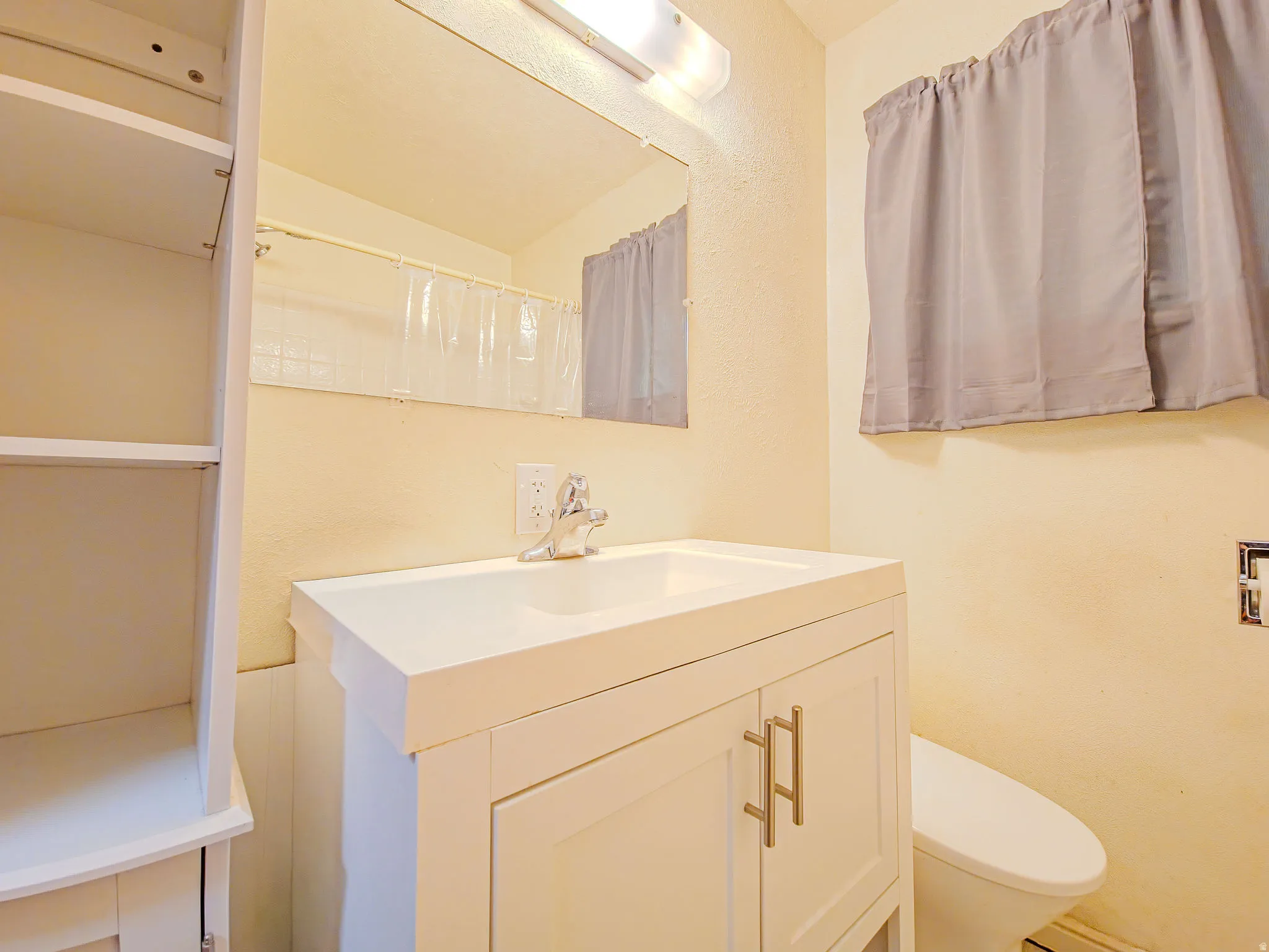 Vanity with integrated sink, chrome faucet, wall-mounted mirror, and built-in shelving
