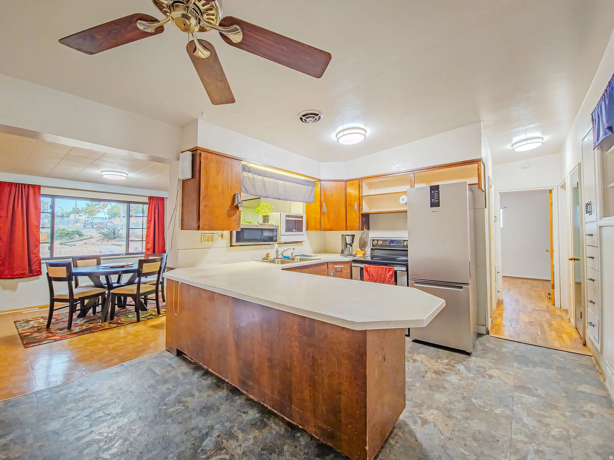 Kitchen featuring wood-finish cabinetry, stainless steel appliances, and a peninsula with countertop seating