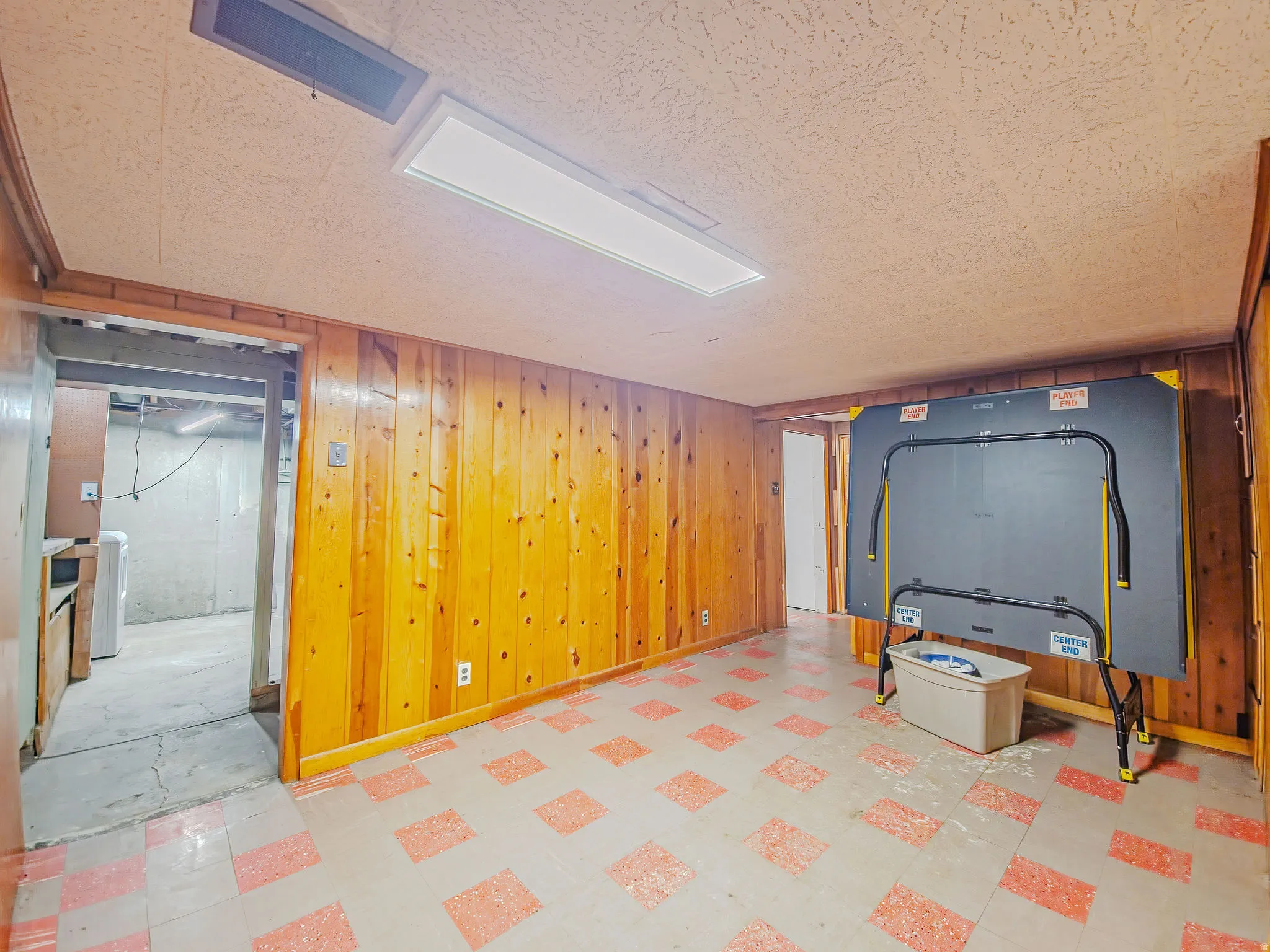 Wood-paneled room with patterned flooring and a drop ceiling with integrated lighting