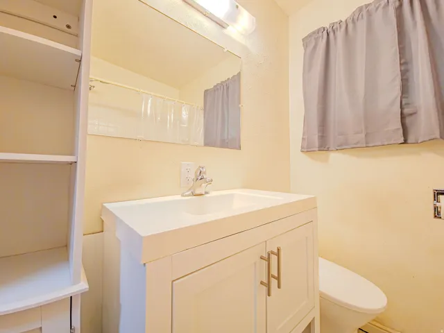 Vanity with integrated sink, chrome faucet, wall-mounted mirror, and built-in shelving