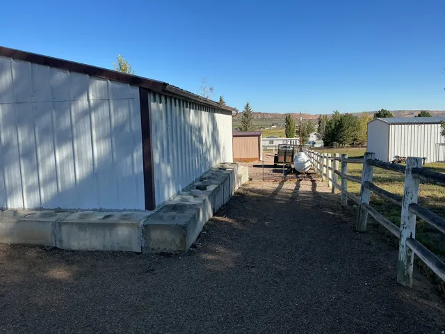 Metal-sided structure with brown trim, concrete block foundation, and gravel ground cover