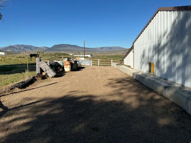 Metal-sided structure with a brown trim roofline, yellow-framed window, and gravel ground cover