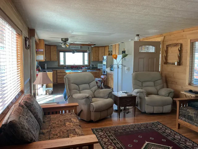 Open-concept living space featuring wood-finish flooring, wood paneling, and window blinds