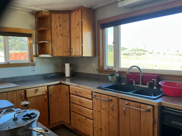 Wood-paneled cabinetry with corner shelving, a double basin sink with a high-arc faucet, and expansive windows