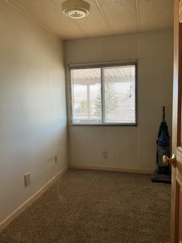 Carpeted flooring, window with blinds, ceiling-mounted light fixture, paneling detail