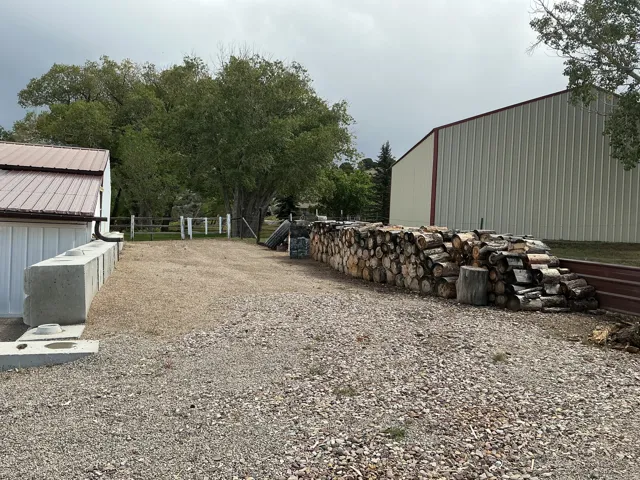 Gravel driveway with a white painted fence and mature trees