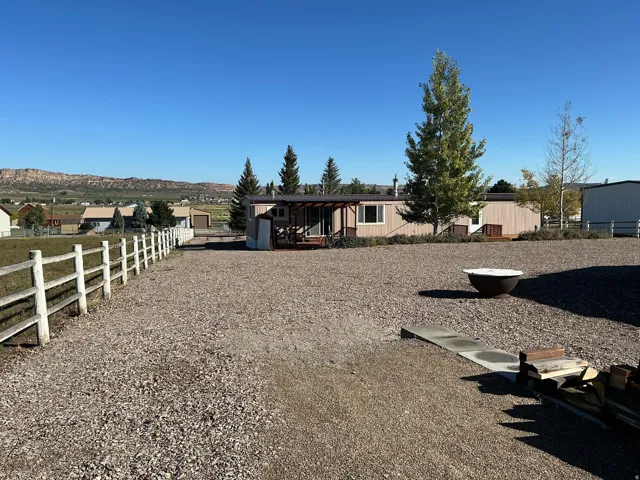 Gravel driveway with a white split-rail fence and distant mountain range