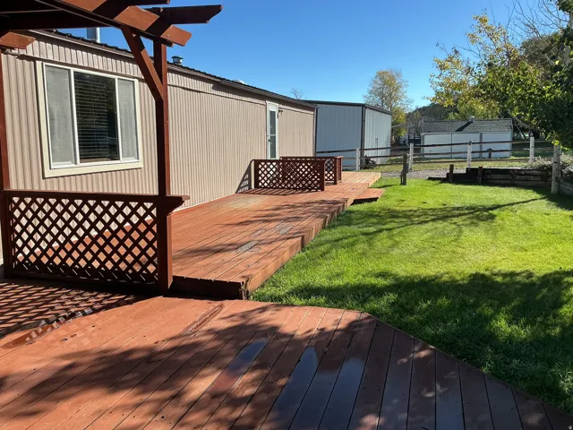 Expansive wooden deck with lattice railing, an integrated pergola, and a grassy yard area