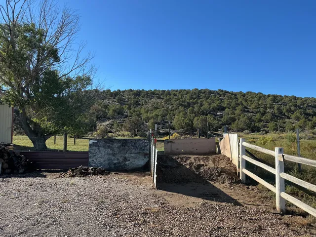 Gravel driveway with a rustic wood fence and a concrete wall