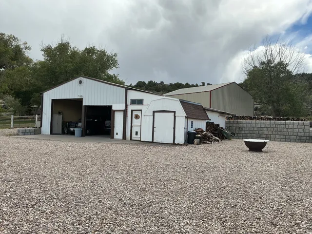 Multiple outbuildings including a large metal-sided structure, an additional shed with an overhead door, and a smaller storage shed with a gambrel roof