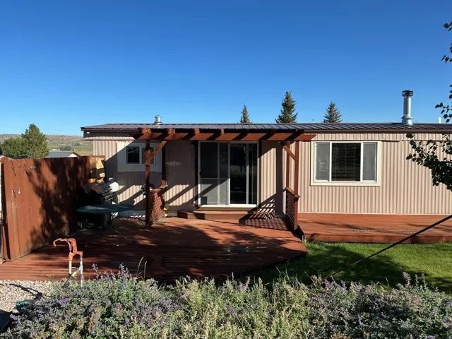 Expansive wooden deck with a pergol, featuring a sliding glass door and multiple windows
