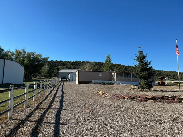 Gravel driveway leading to multiple outbuildings and a screened porch