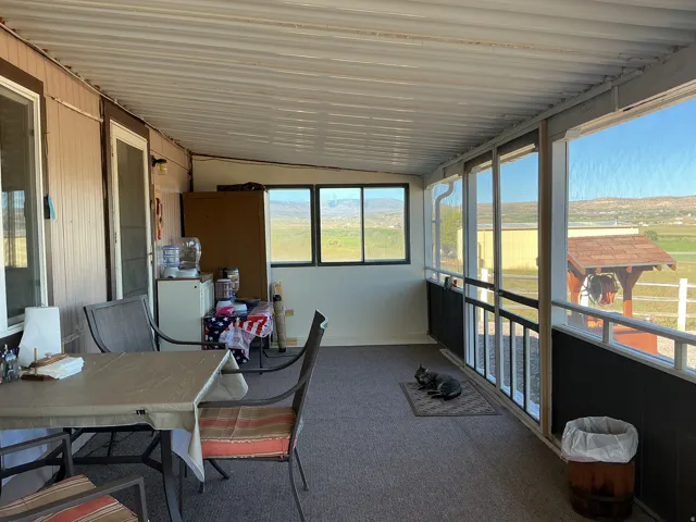 Screened-in porch featuring a corrugated ceiling, wall-mounted light fixture, and windows