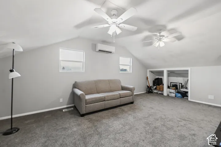 Sloping ceiling with multiple ceiling fans, recessed wall storage, and mini-split HVAC unit