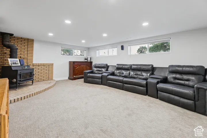 Recessed lighting with a wood-burning stove featuring a brick surround and hearth