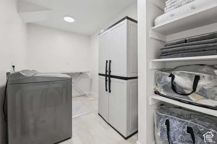Built-in shelving, recessed ceiling light, white cabinetry with black hardware, and light-toned flooring