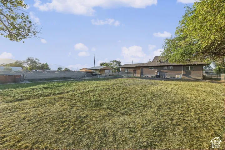 Expansive grassy lot with a brown exterior residence featuring multiple windows and a shingle roof