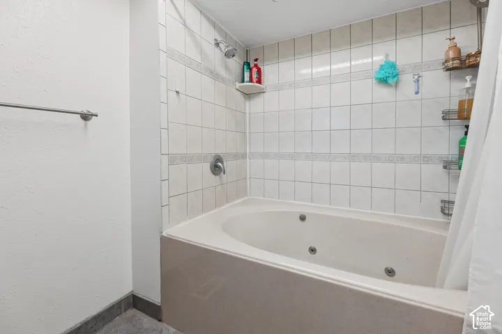 Tiled shower and tub combination featuring a fixed shower head and integrated wall-mounted faucet
