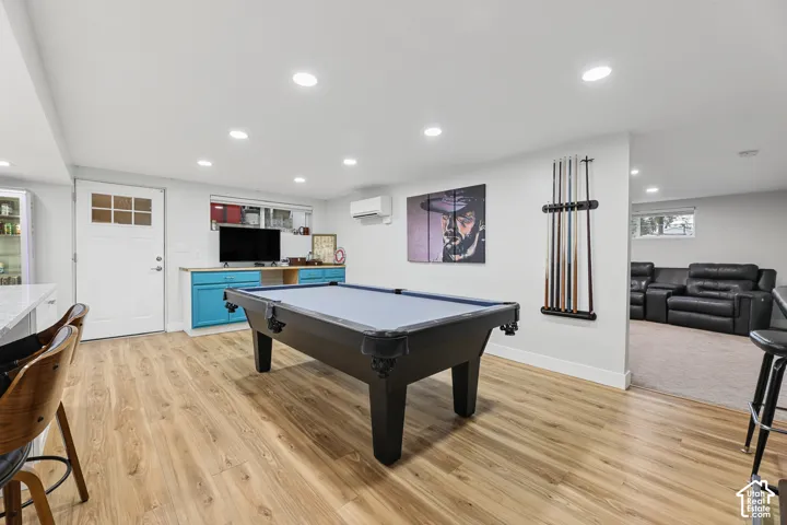Recessed lighting, wood-finish flooring, white cabinetry with glass fronts, a built-in media console with blue cabinetry, and a mini-split system