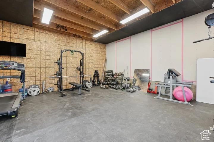 Exposed ceiling joists with recessed lighting, oriented strand board wall finish, concrete flooring