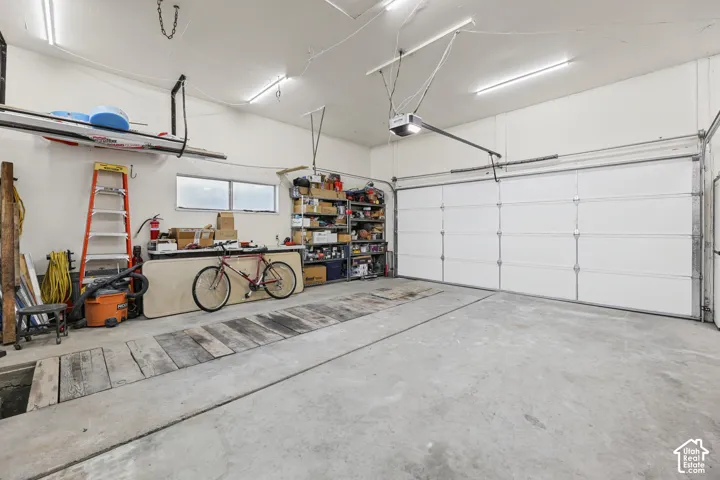 Spacious garage with a concrete floor, overhead lighting, an automatic garage door opener, and horizontal windows