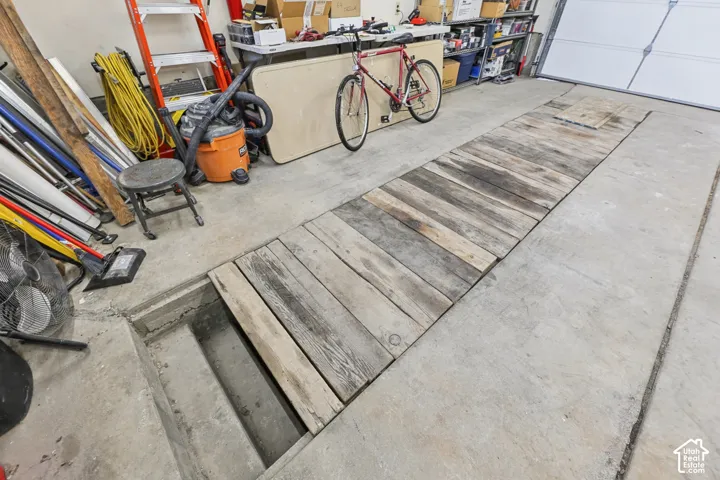 Concrete flooring featuring an in-floor service pit with a wood-plank cover