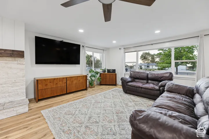 Recessed lighting, ceiling fan, wood-finish flooring, white stone veneer fireplace, and expansive windows