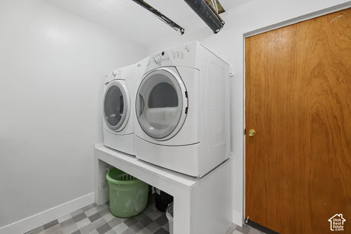 White front-loading laundry machines on a raised platform, wood-finish door, and patterned floor tile