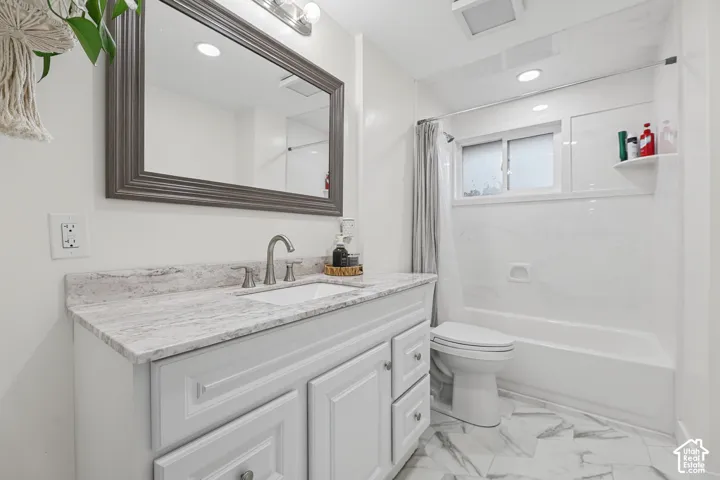 White vanity with panel-front cabinetry, a light-toned countertop, and an undermount sink