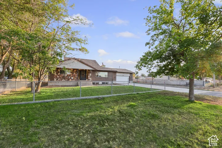 Exterior featuring stone veneer and brick siding, a visible garage, and a chain-link fence